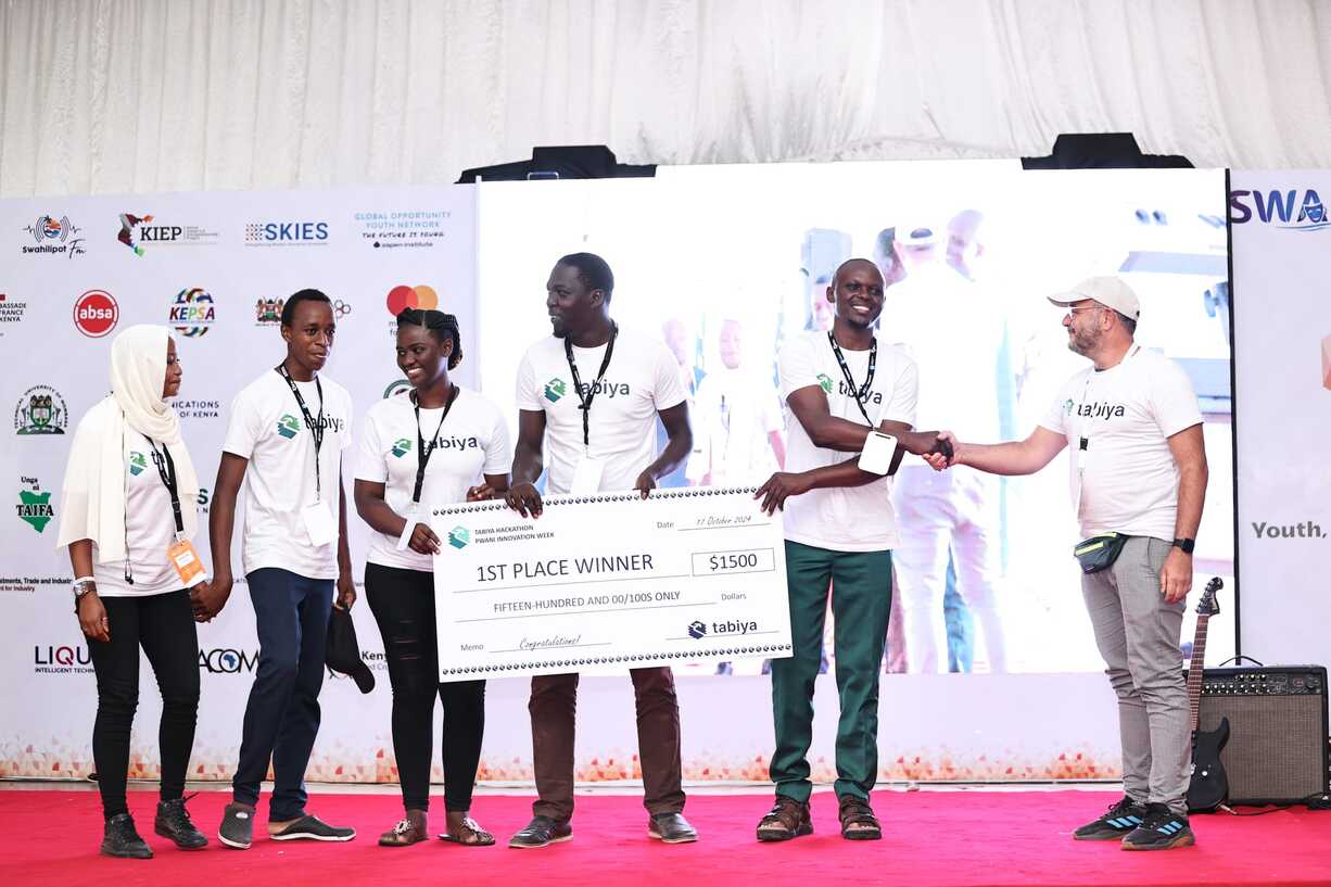 Team receives large 1st place winner cheque on stage at a youth innovation event.