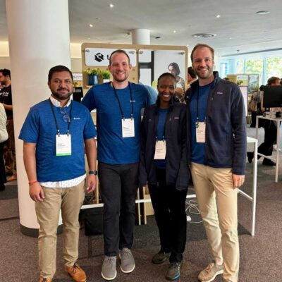 Group of four smiling attendees pose for a photo at a tech or social impact event.