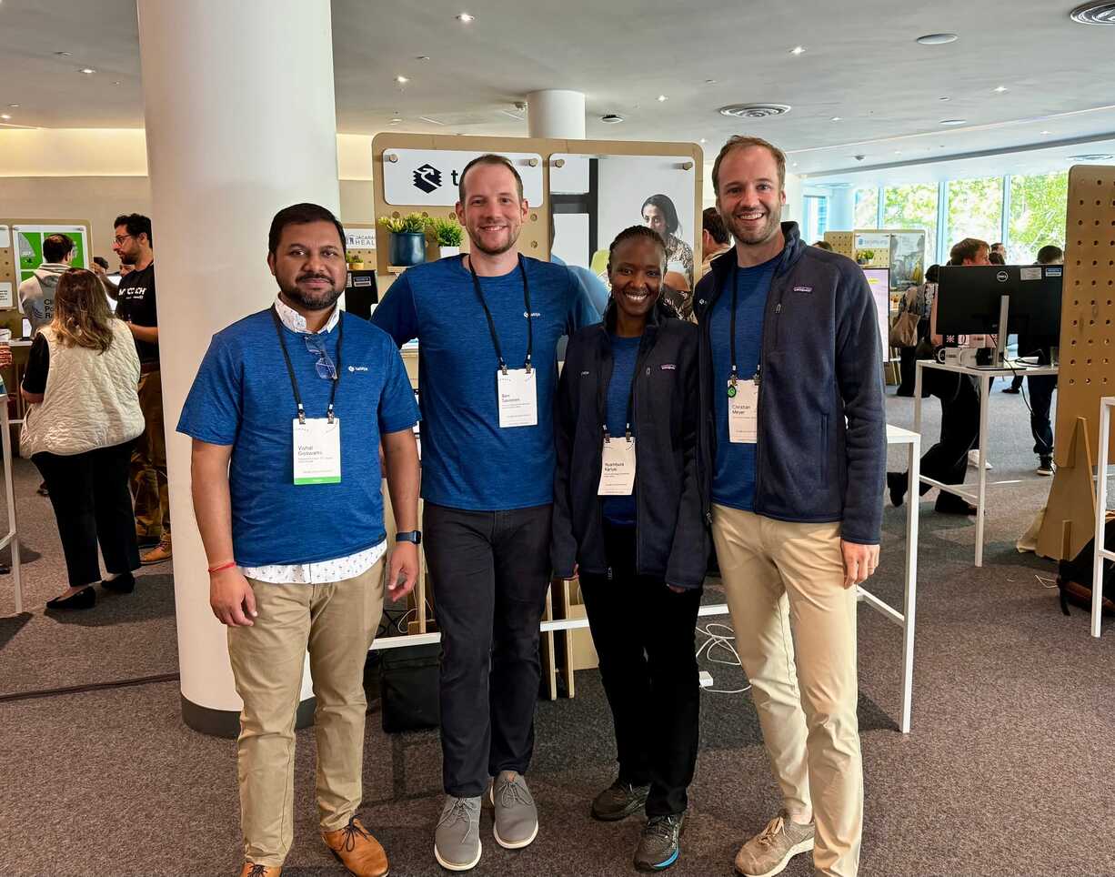 Group of four smiling attendees pose for a photo at a tech or social impact event.