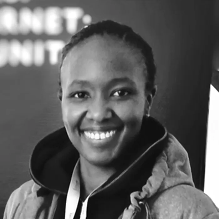Black-and-white photo of a smiling woman in a hoodie at a professional event.